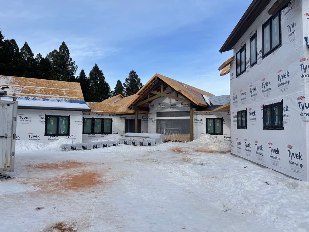 New construction home in winter, featuring Tyvek wrap and snow-covered surroundings.