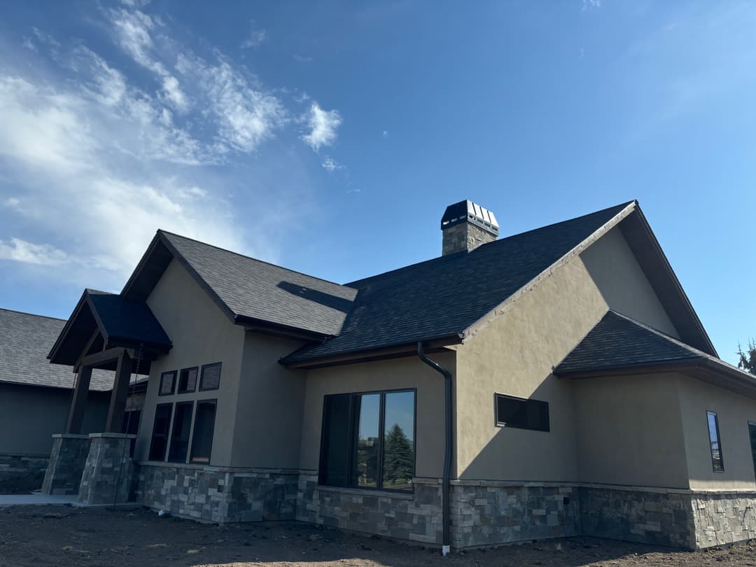 Modern single-story home featuring stone accents and a prominent chimney under blue skies.
